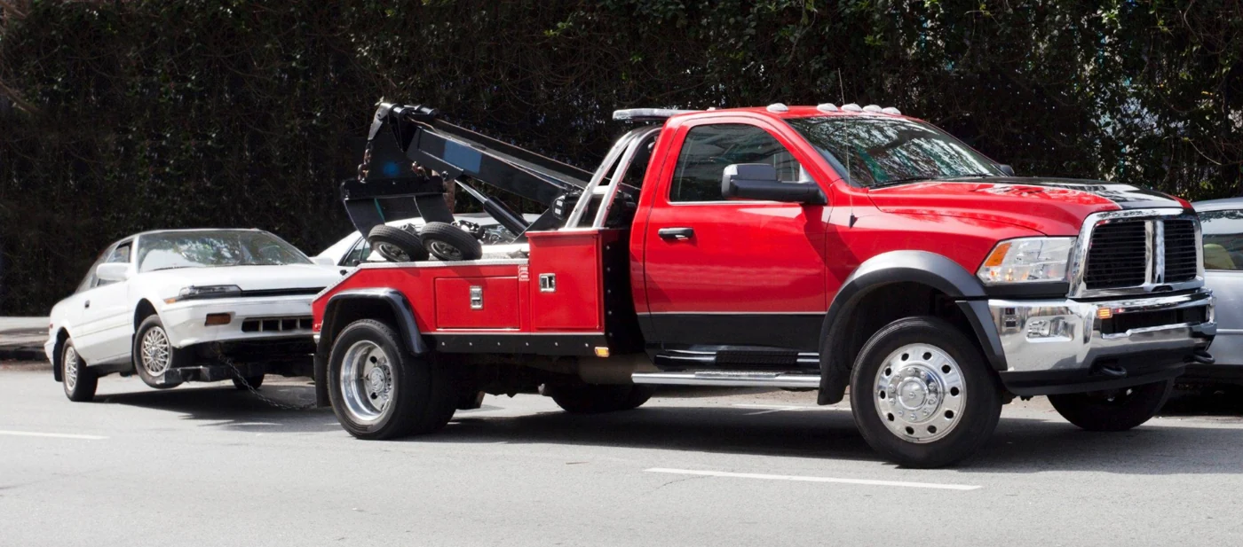 Red tow truck transporting a vehicle, from the existing Big Red website